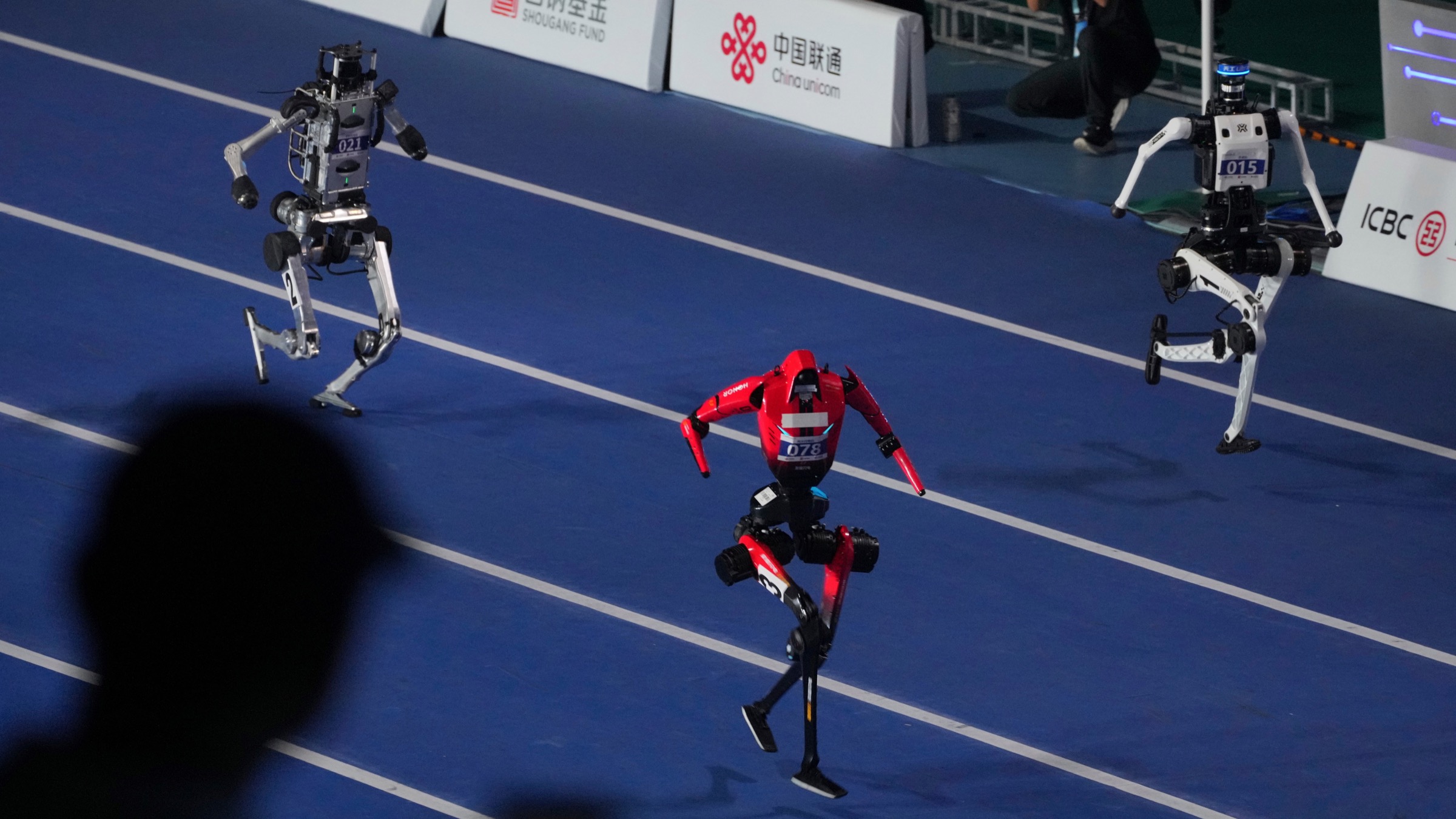 Three humanoid robots run on the track during the opening of the 2026 World Humanoid Robot Games in Beijing