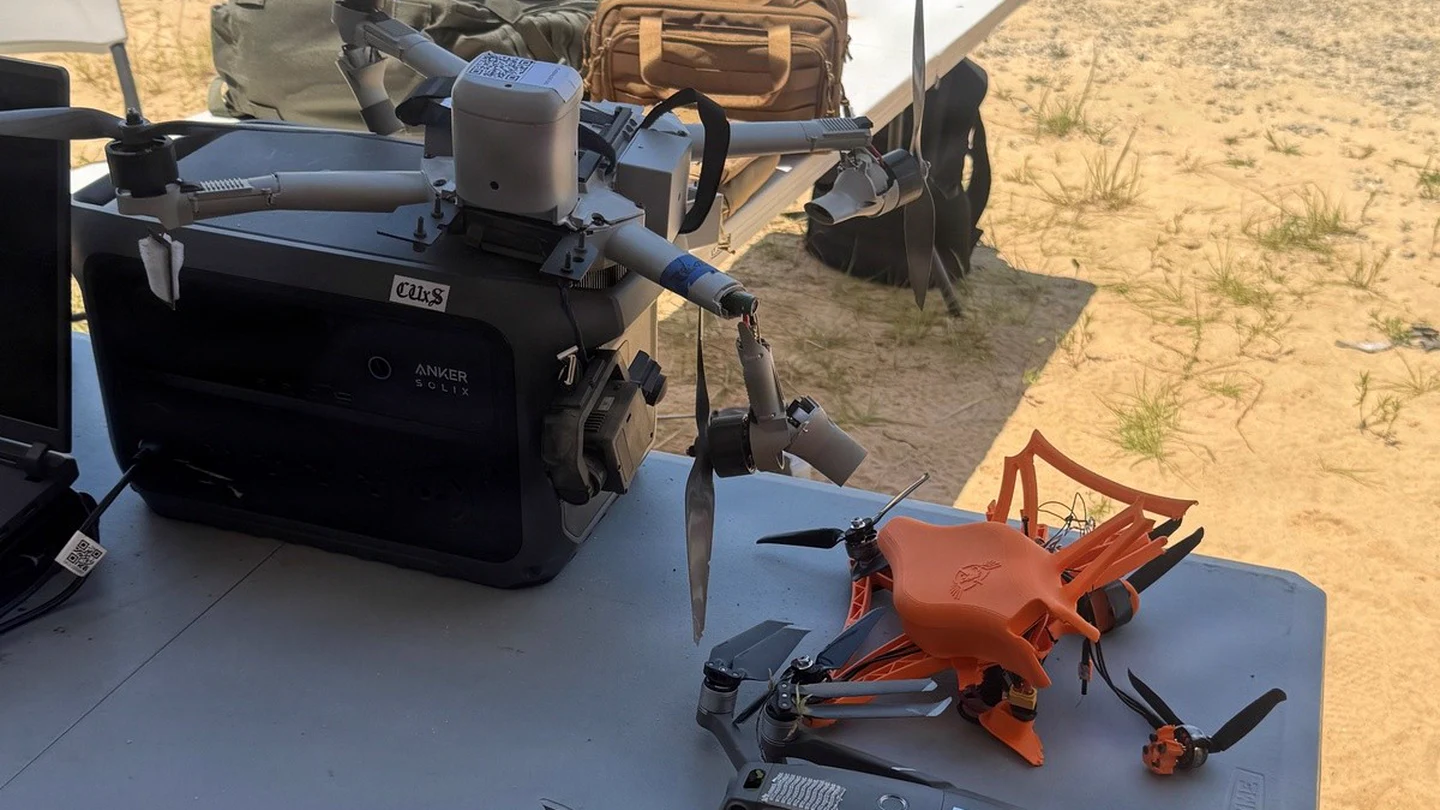 A Bumblebee V2 counter-drone interceptor and other training drones rest on a field table at Fort Benning