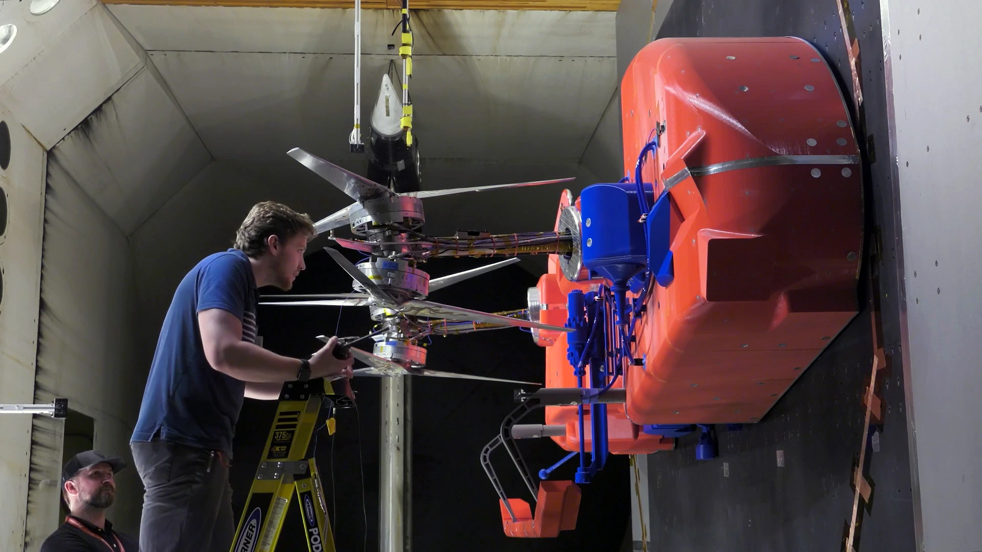 Engineers adjust Dragonfly test-model rotors in NASA Langley’s wind tunnel. Archive photograph of physical testing, separate from the new avionics simulation.