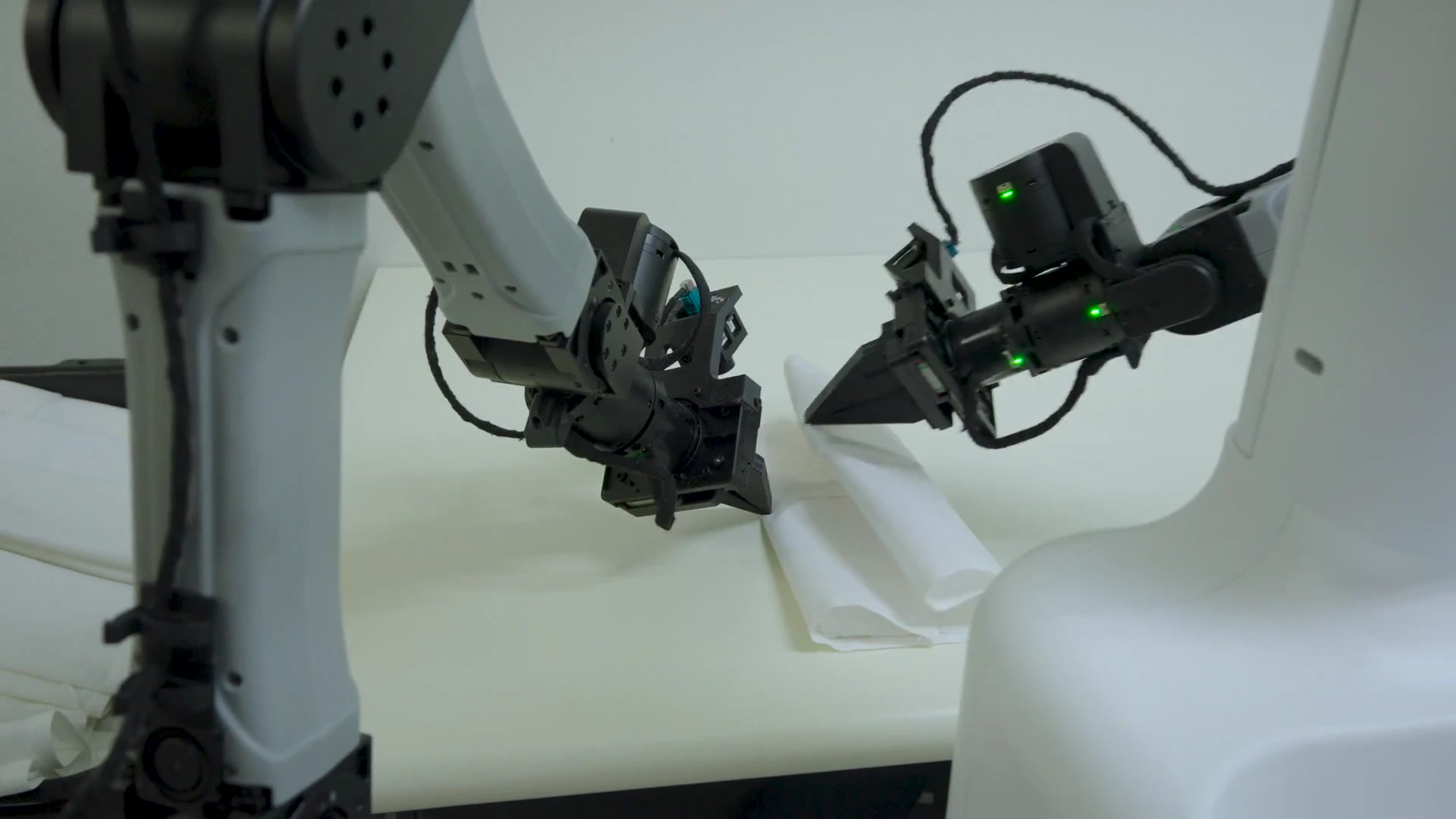 Dyna Robotics robot folds a white napkin with two grippers at a production station