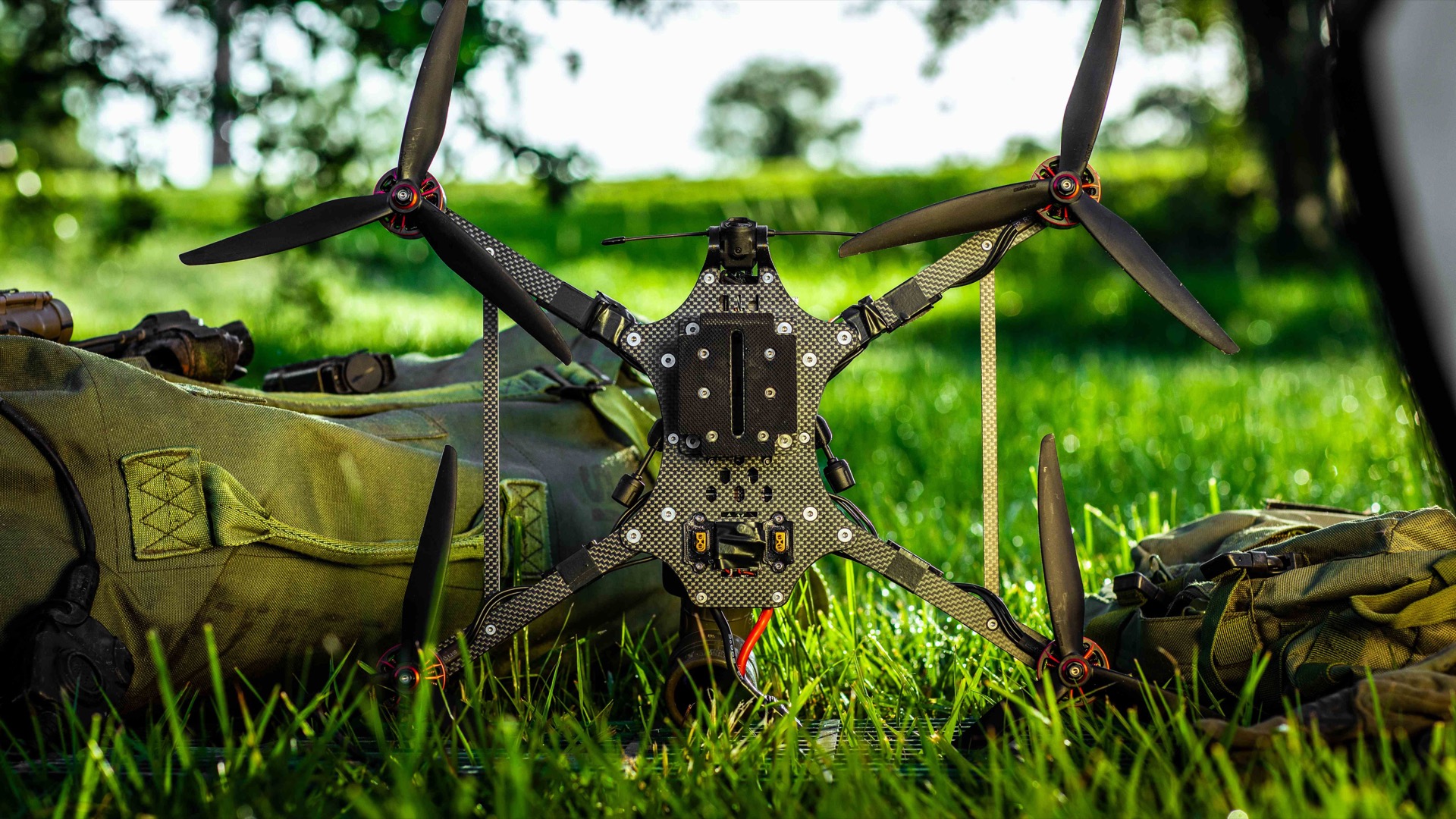 A Powerus tactical FPV drone resting on field equipment in grass