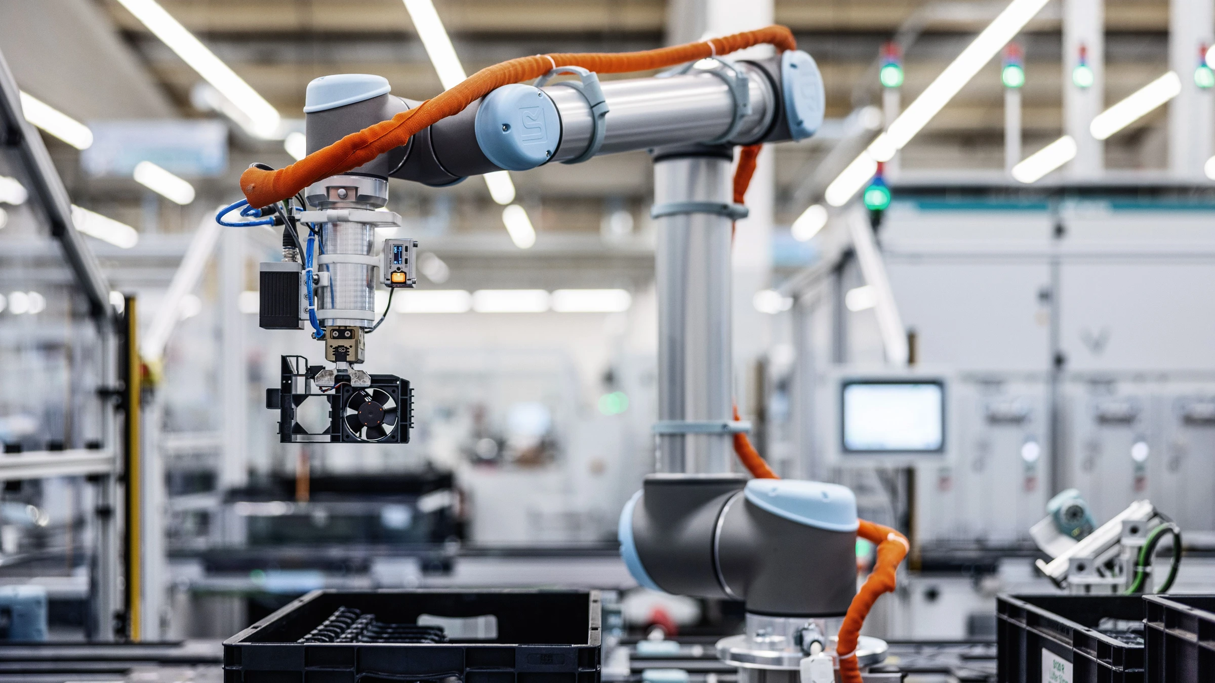 An industrial robot grips a fan assembly at Siemens’ Erlangen electronics factory, in a company-supplied context photograph.