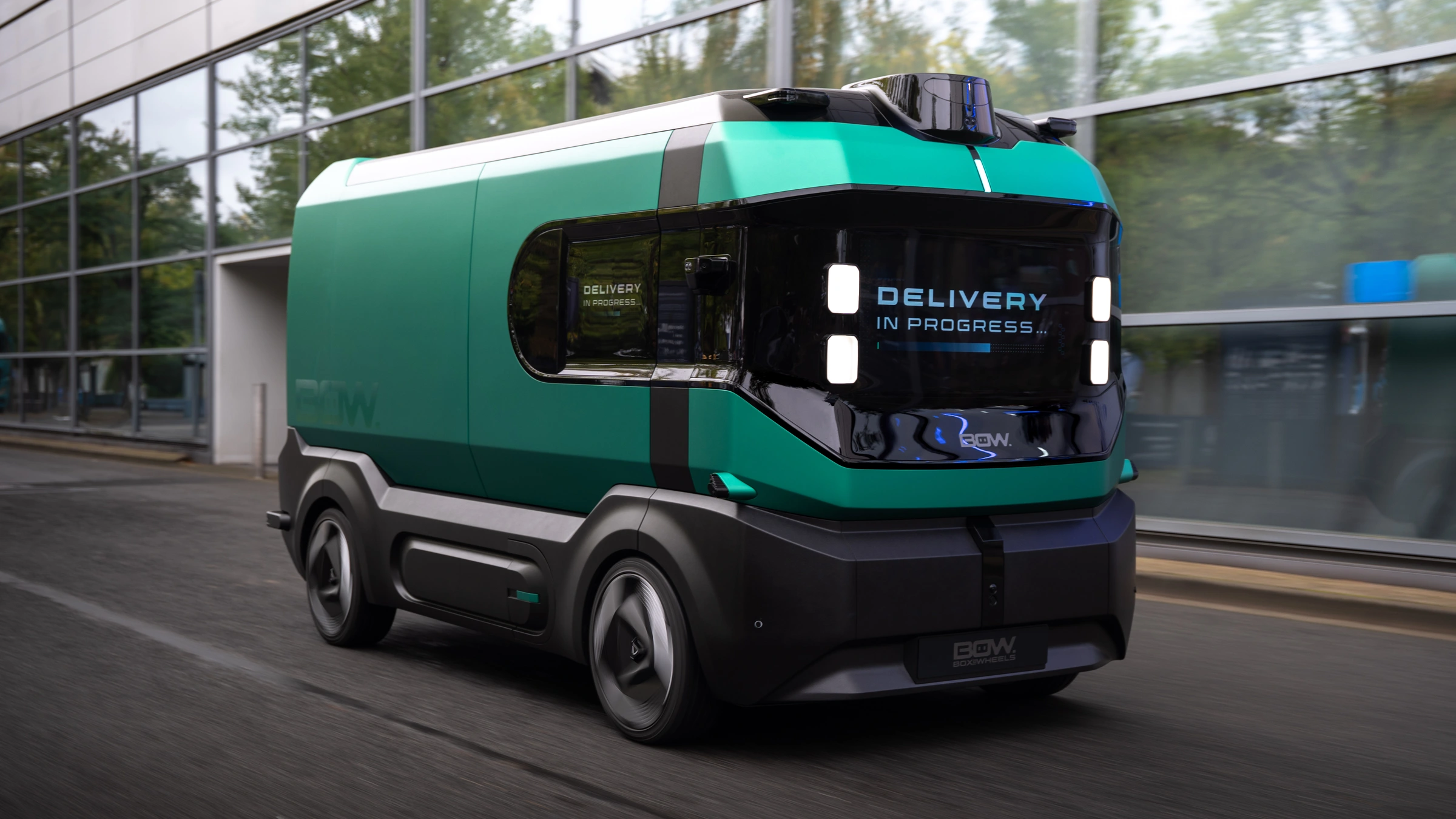 A green and black BOW concept delivery vehicle beside a glass-fronted building in an official Stellantis press photograph.