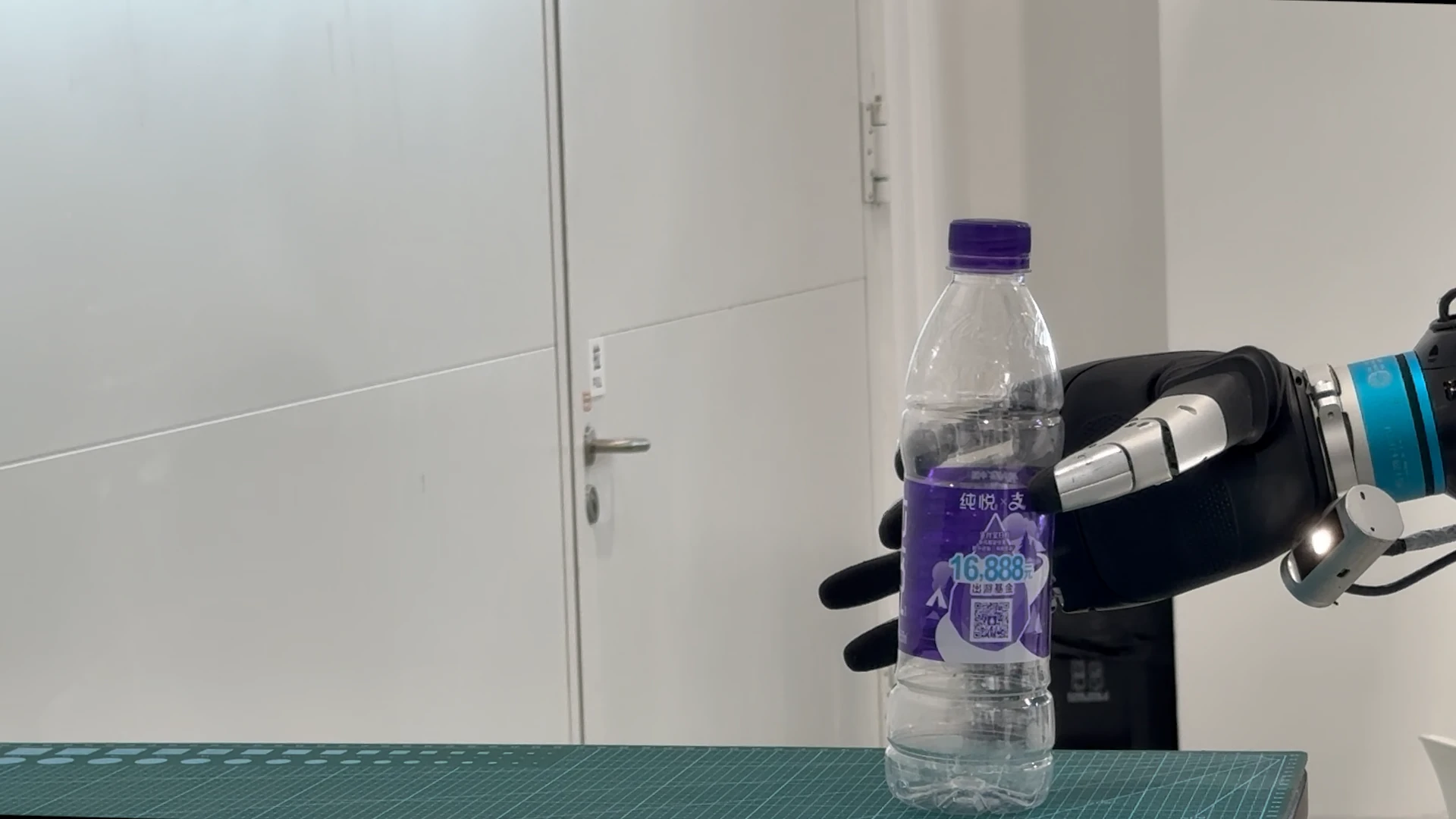 A ViTacPhys dexterous robot hand holds a clear plastic bottle during an adaptive-grasping rollout.
