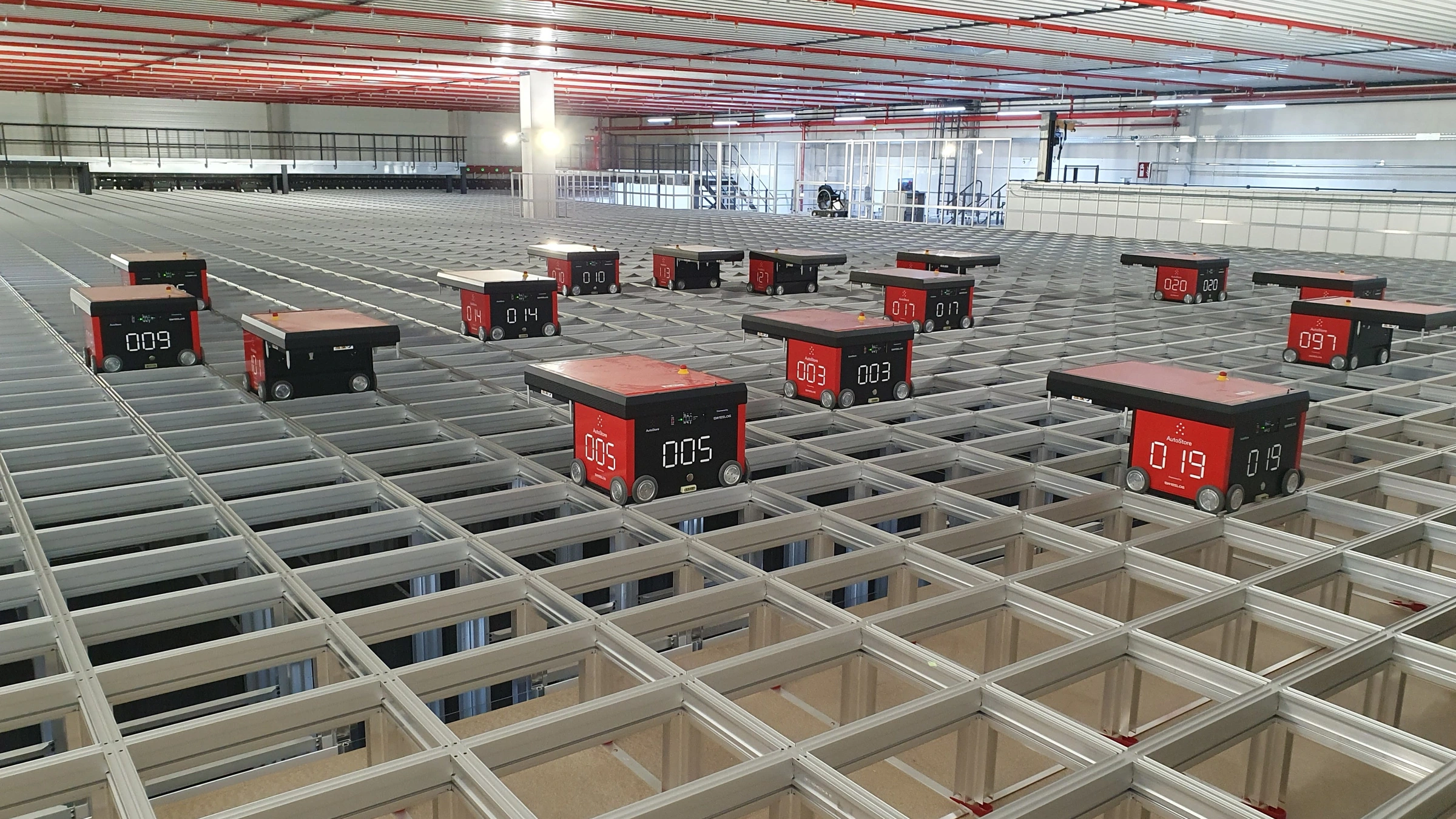 Archive photograph of red AutoStore robots on an indoor storage grid, photographed on 18 July 2025.