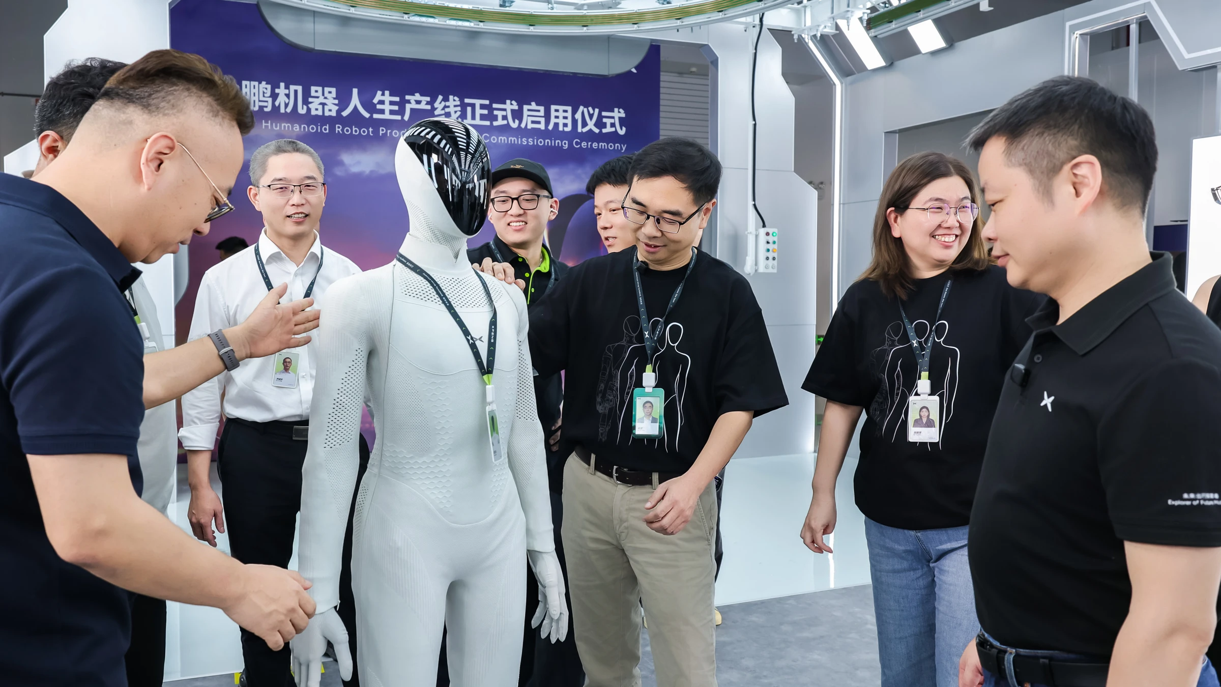 An XPENG IRON humanoid stands among people at the robot production-line commissioning ceremony in Guangzhou.